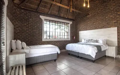 a bedroom with two beds and a brick wall at The Guest Villa in Benoni