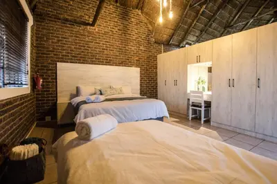 a bedroom with two beds and a brick wall at The Guest Villa in Benoni