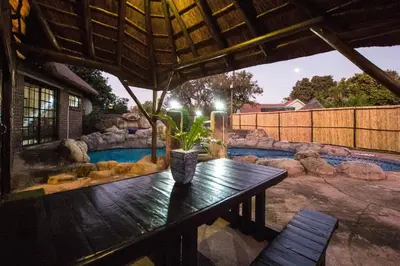 a patio with a wooden table and a pool at The Guest Villa in Benoni