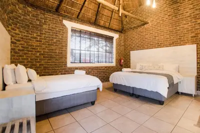 two beds in a room with a brick wall at The Guest Villa in Benoni