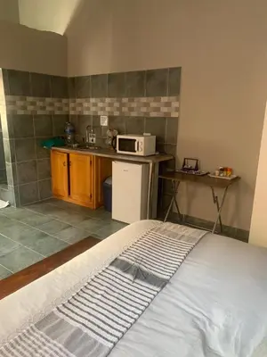 a room with a kitchen with a bed and a microwave at MAM in Mokopane