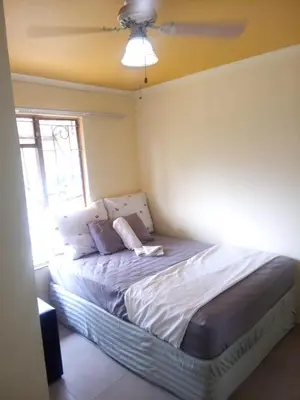 a bed in a bedroom with a ceiling fan at Kempton Park Lodge Birch Acres Kempton Park in Kempton Park