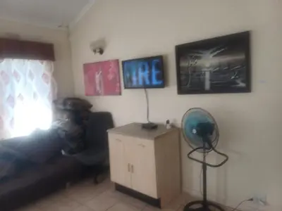 a living room with a couch and a fan at Kempton Park Lodge Birch Acres Kempton Park in Kempton Park