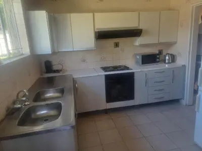 a kitchen with white cabinets and a sink and a microwave at Kempton Park Lodge Birch Acres Kempton Park in Kempton Park
