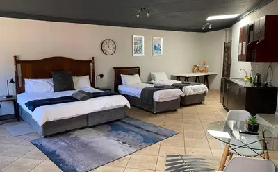 a bedroom with two beds and a table and a table sidx sidx at Waterkloof Glen Guest House in Pretoria