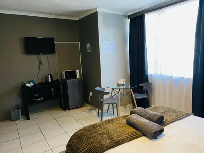 a hotel room with a bed and a table with chairs at Waterkloof Glen Guest House in Pretoria