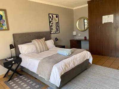 a bedroom with a bed with a mirror on the wall at Waterkloof Glen Guest House in Pretoria