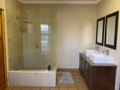 a bathroom with two sinks and a shower at Waterkloof Glen Guest House in Pretoria