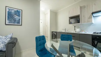 a kitchen with a glass table and blue chairs at Chic Modern Midrand Escape in Midrand