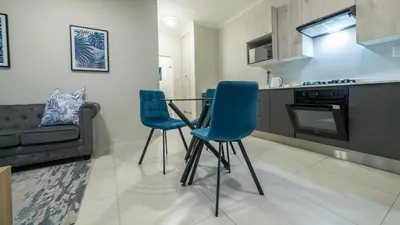 a kitchen with two blue chairs and a table at Chic Modern Midrand Escape in Midrand