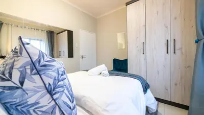 a bedroom with a bed and a wooden cabinet at Chic Modern Midrand Escape in Midrand