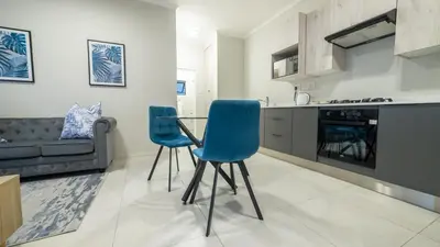 a kitchen with a table and two blue chairs at Chic Modern Midrand Escape in Midrand