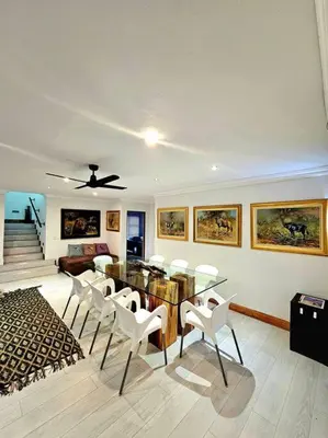 a living room with a table and white chairs at Luxury GuesthouseCo RiverHouse in Marloth Park