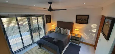 a bedroom with a bed and a large window at Luxury GuesthouseCo RiverHouse in Marloth Park