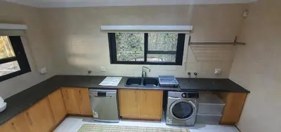 a small kitchen with a sink and a washing machine at Luxury GuesthouseCo RiverHouse in Marloth Park