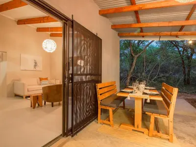 a dining room with a wooden table and chairs at Monkeys Tail in Marloth Park