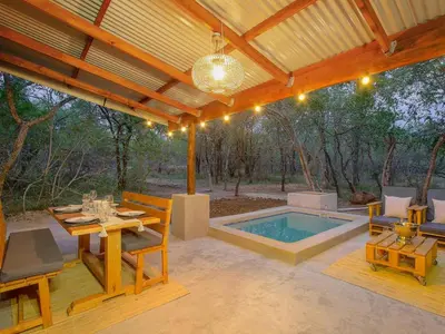 a patio with a table and a swimming pool at Monkeys Tail in Marloth Park