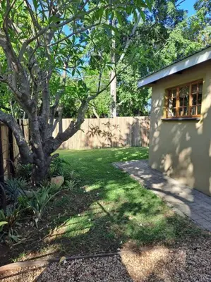a yard with a house and a tree and a fence at Wild Fig Accommodation in Tzaneen
