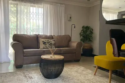 a living room with a brown couch and a yellow chair at Gorgeous 2-Bedroom apartment in Secunda