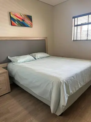 a bedroom with a large bed with white sheets and a window at House of Grace with Backup power Next to OR Tambo in Kempton Park