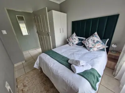 a bedroom with a large bed with towels on it at Botle Hive in Kempton Park