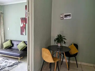 a room with a table and chairs and a couch at Botle Hive in Kempton Park