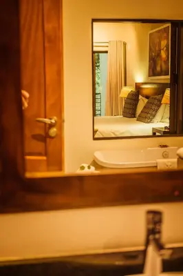 a bathroom mirror with a bed in the reflection at Bushveld Terrace Safari Hotel, Lodge & Spa in Phalaborwa