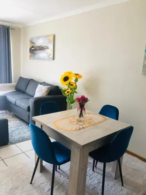 a living room with a table and blue chairs at Menlyn Hub Accommodation in Pretoria