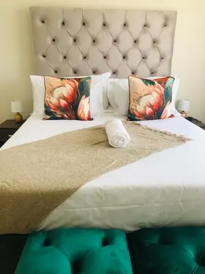 a bedroom with a bed with a headboard and pillows at Menlyn Hub Accommodation in Pretoria