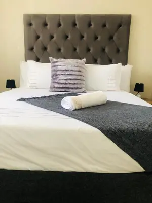 a bedroom with a large bed with a large headboard at Menlyn Hub Accommodation in Pretoria