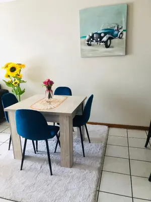 a dining room table with chairs and a vase of flowers at Menlyn Hub Accommodation in Pretoria