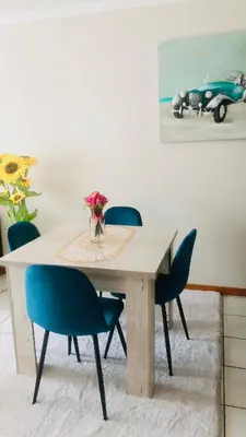 a dining room table with chairs and a vase of flowers at Menlyn Hub Accommodation in Pretoria