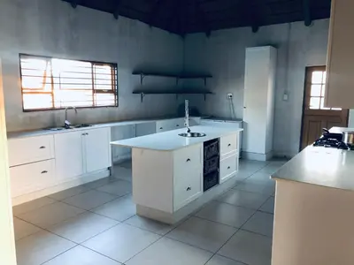 a large kitchen with white cabinets and a sink at In The Bush Farm Lodge in Winterveld