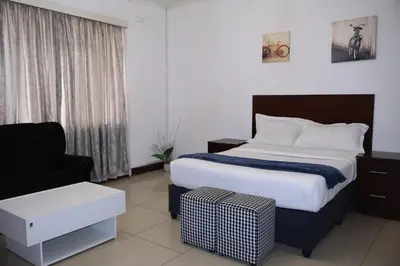 a bedroom with a bed and a couch and a chair at Khaya Mnandi Leisure Suites in Pretoria