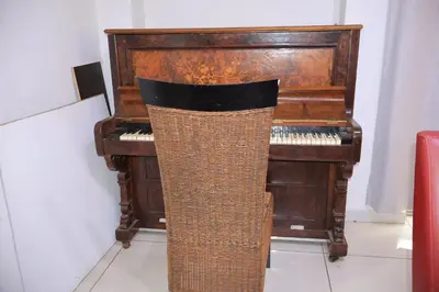 an old piano with a wicker chair in front of it at Khaya Mnandi Leisure Suites in Pretoria