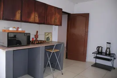 a kitchen with a counter with a microwave and a stool at Khaya Mnandi Leisure Suites in Pretoria