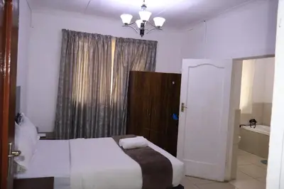 a bedroom with a bed and a bathroom with a window at Khaya Mnandi Leisure Suites in Pretoria