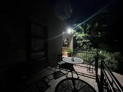 a table and chairs on a balcony at night at Hillside Manor in Dalmada AH