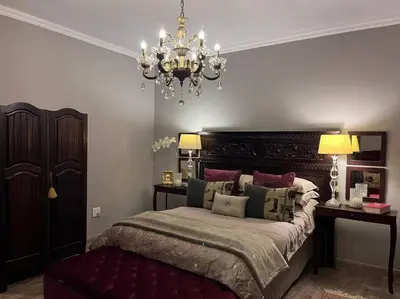 a bedroom with a large bed and a chandelier at Hillside Manor in Dalmada AH