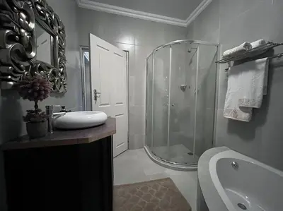 a bathroom with a shower and a sink and a tub at Hillside Manor in Dalmada AH
