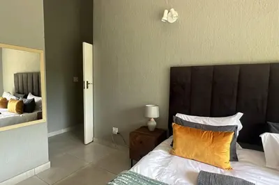 a bedroom with a bed with a brown headboard and a mirror at Serenity Farm House in Karino