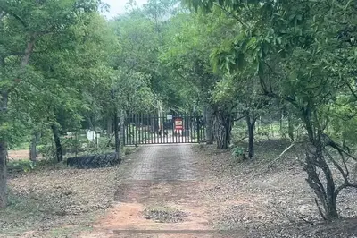 a dirt road with a gate and some trees at Serenity Farm House in Karino