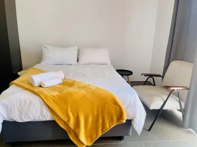 a bedroom with a bed with a yellow blanket and a chair at TrendyBliss Guest House - n0016 in Northam