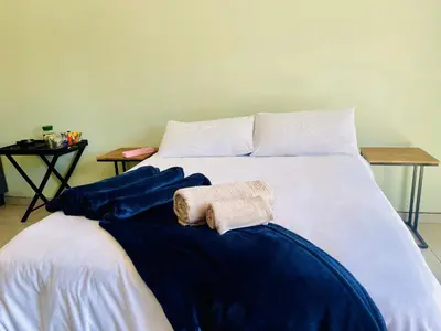 a white bed with blue sheets and towels on it at TrendyBliss Guest House - n0016 in Northam