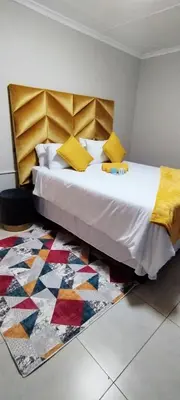 a bedroom with a large bed and a rug at Reutlwane Gardens Apartments in Secunda