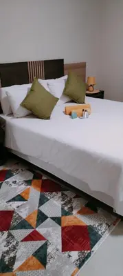 a bedroom with a white bed with a colorful rug at Reutlwane Gardens Apartments in Secunda
