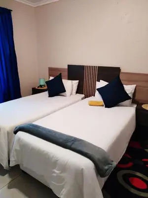 two beds sitting next to each other in a room at Reutlwane Gardens Apartments in Secunda