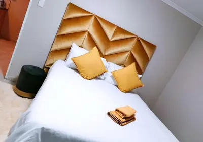 a bedroom with a white bed with yellow pillows at Reutlwane Gardens Apartments in Secunda