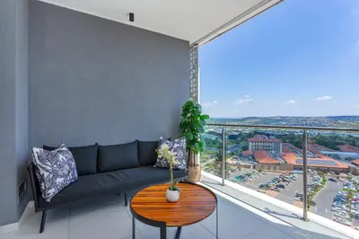 a living room with a couch and a large window at Ellipse Waterfall on Magwa cres in Midrand