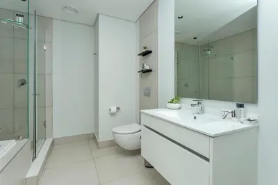 a white bathroom with a toilet and a sink at Ellipse Waterfall on Magwa cres in Midrand